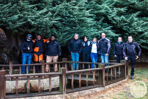 Grupo de personas posando junto a un cercado de madera en un entorno arbolado.